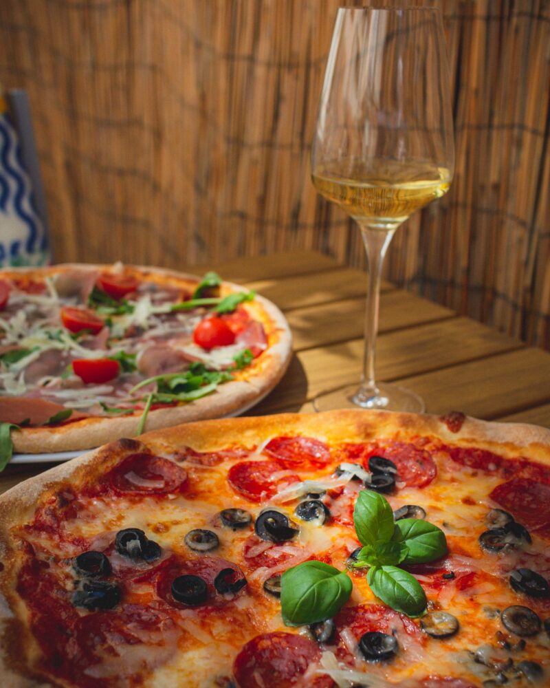 Pizzaer og et glas hvidvin på et dækket træbord