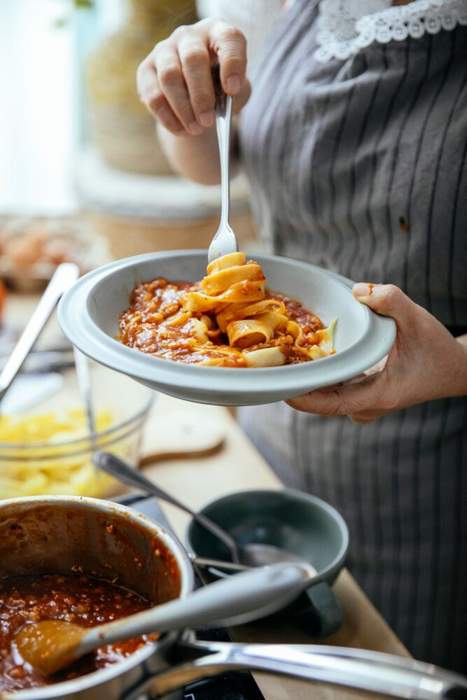 En person serverer pasta og løfter en portion med gaflen