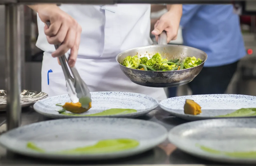 Kok anretter grøntsager i et professionelt restaurantkøkken
