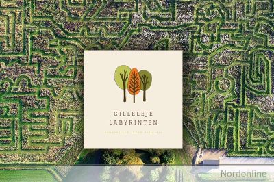 Gilleleje Labyrintens logo over et luftfoto af labyrintens grønne stier