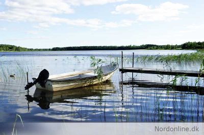 Lille båd ligger ved en bådebro i en sø