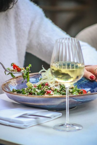 Gæst spiser en salat ved et dækket bord med hvidvin