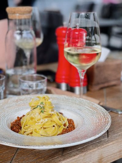 Tagliatelle og et glas hvidvin på et restaurantbord