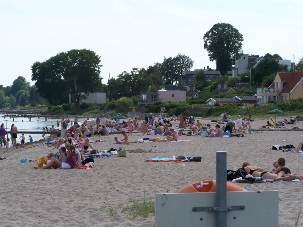 Badegæster på sandstranden i Espergærde med kystens huse i baggrunden