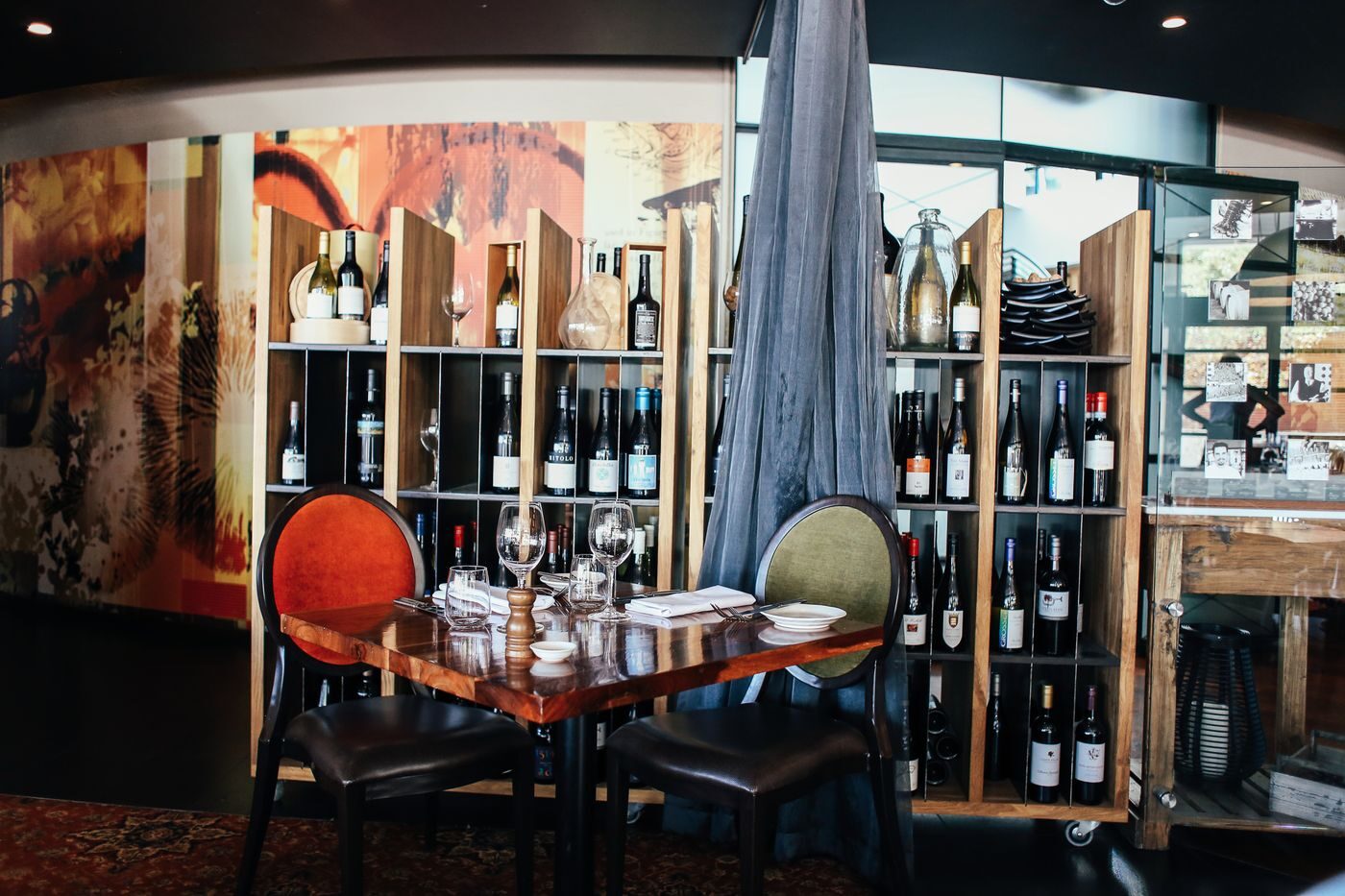 Dækket restaurantbord med vinflasker på hylder i baggrunden