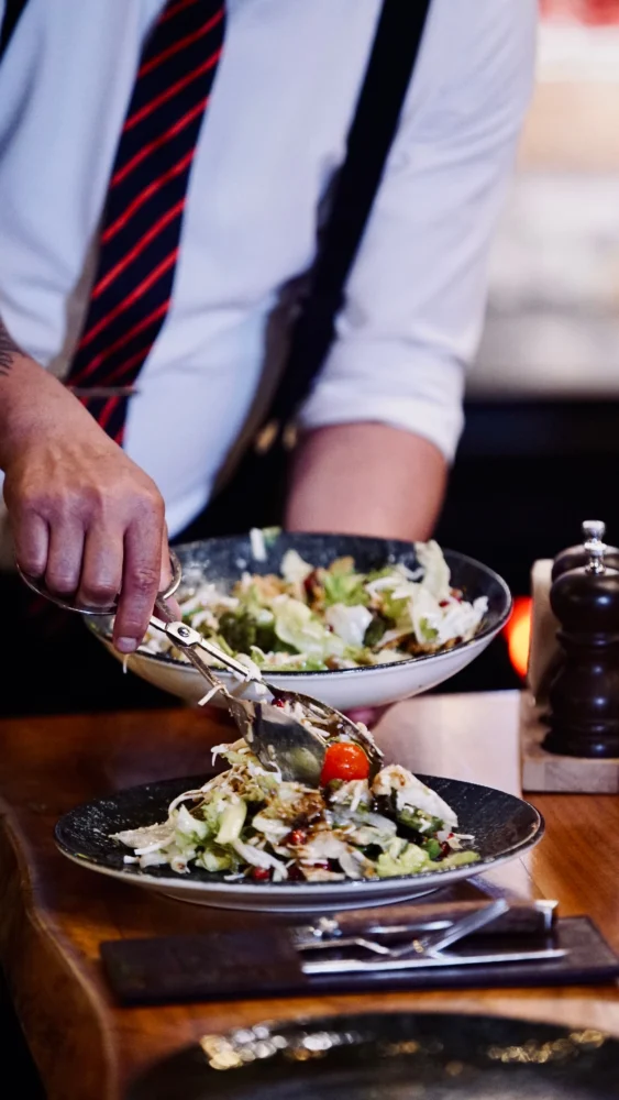 Kok anretter frisk salat med en pincet