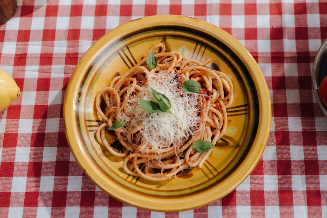 Pasta med tomatsauce, ost og basilikum på en ternet dug