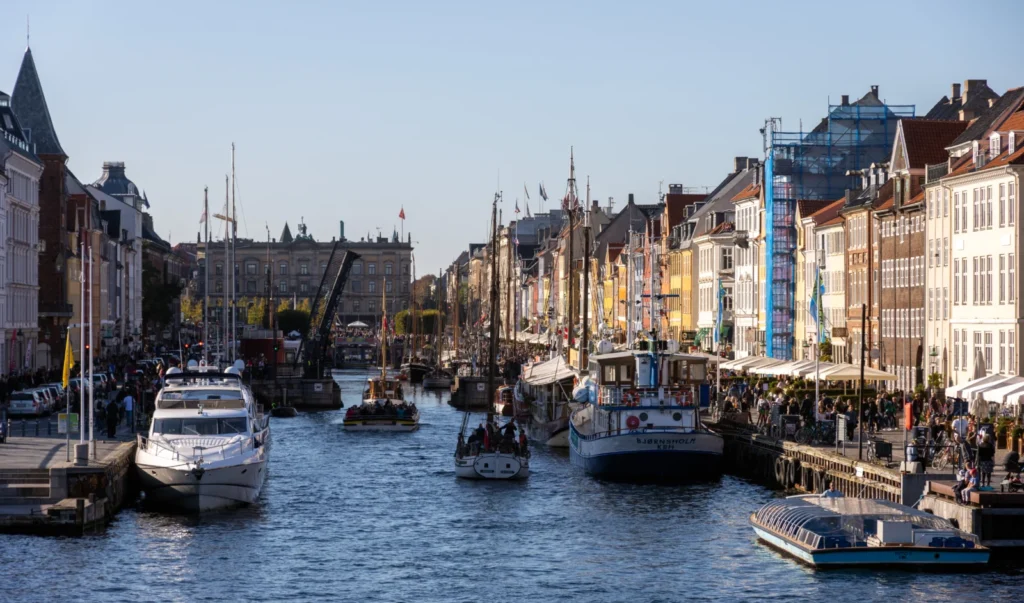 Både, farverige huse og gæster langs Nyhavn i solskin