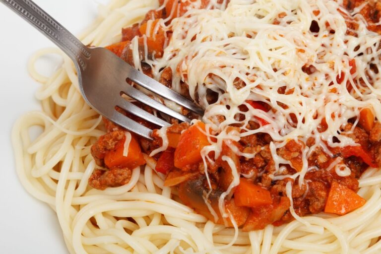 Spaghetti med kødsauce og revet ost på en tallerken