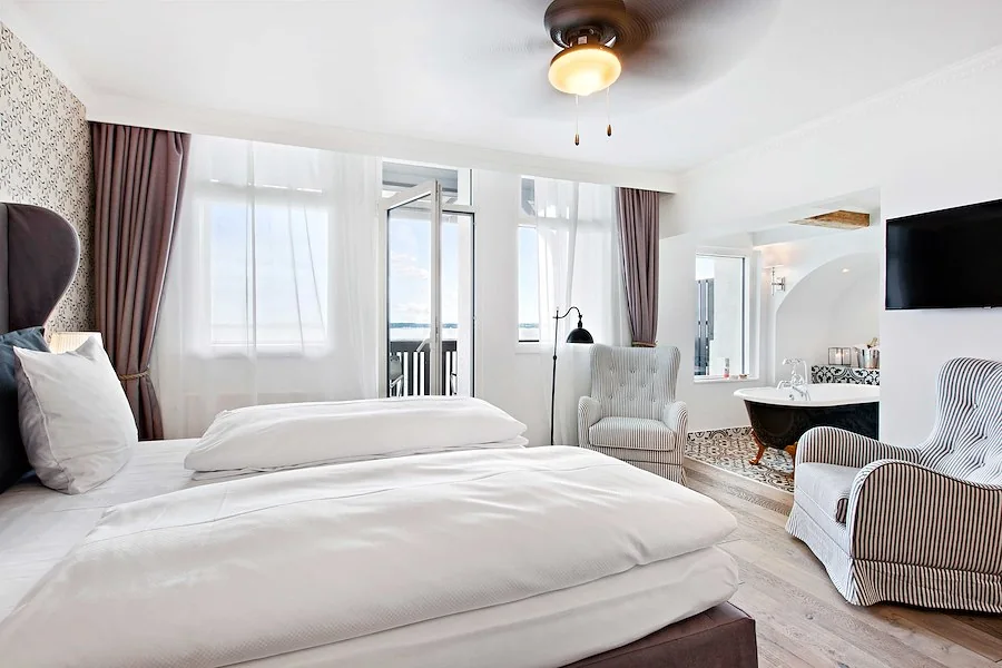 Juniorsuite på Marienlyst Strandhotel med hvid dobbeltseng og udsigt mod Øresund