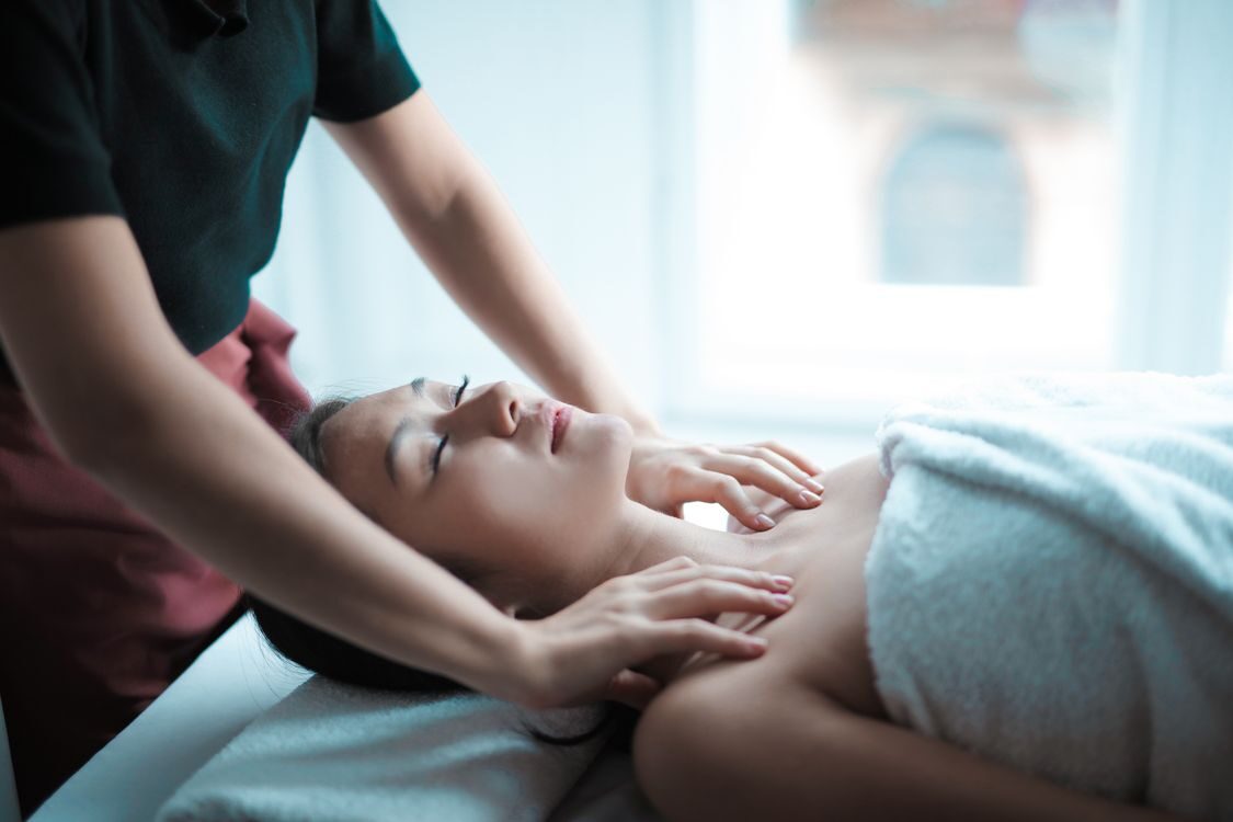 Kvinde får nakke- og skuldermassage på en briks i et lyst rum