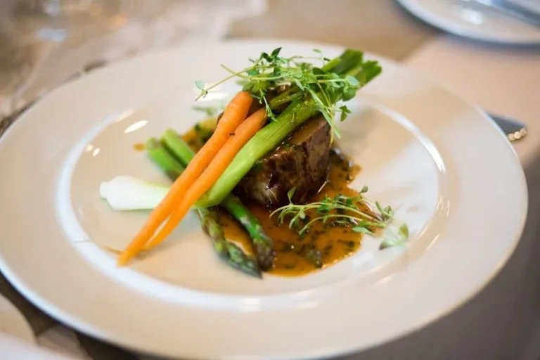 Kød med grøntsager og sauce på en hvid tallerken