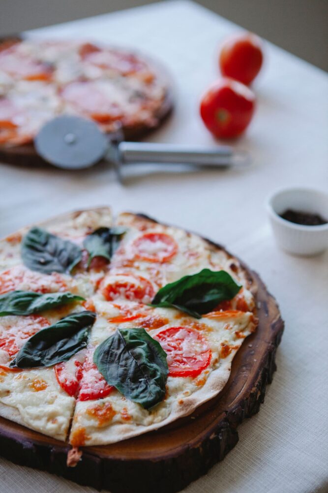 Pizza med tomat og frisk basilikum på et træbræt