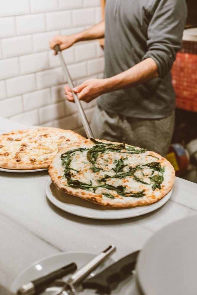 Pizzabager lægger en frisk pizza på en tallerken