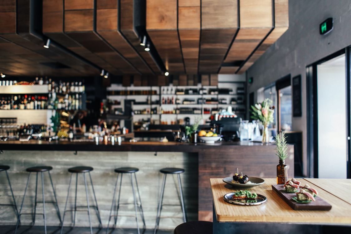 Restaurant med træborde, bar og små retter ved vinduet