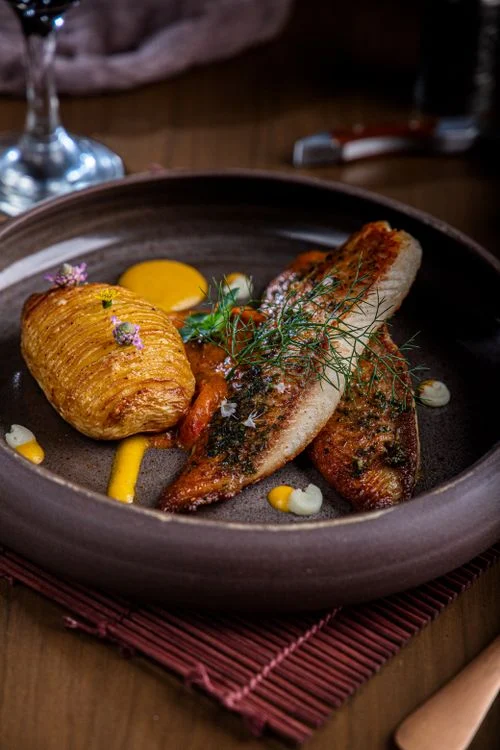 Fiskefilet med urter og kartofler på en rustik tallerken